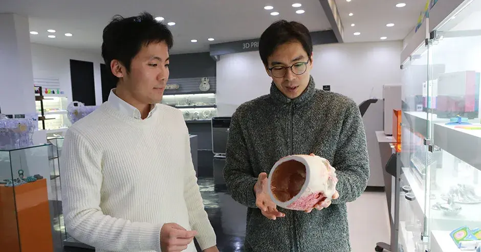 2 colegas mirando una impresión 3D