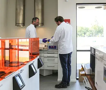 Persona en un laboratorio odontológico rodeada por impresoras 3D y equipamientos de laboratorio