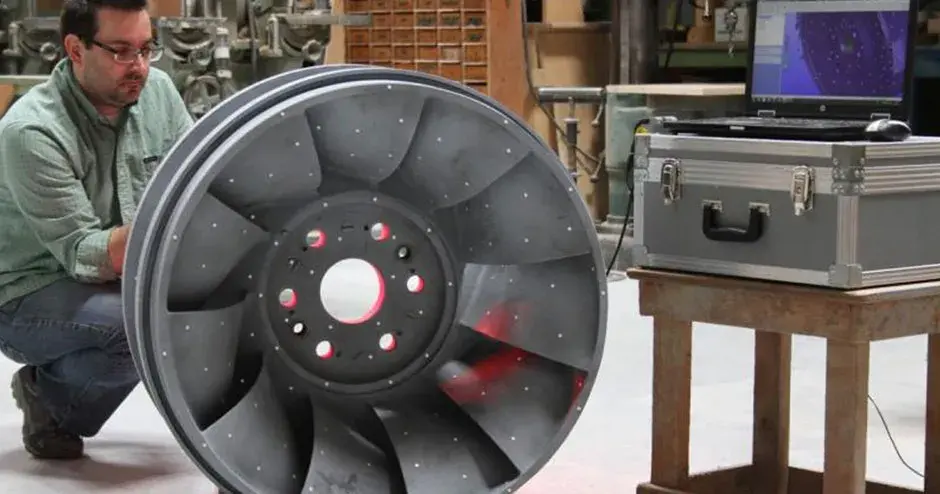 una persona de pie junto a una pieza de microfusión en un entorno industrial