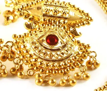 diseño complejo de un arete de oro con un conjunto de rubíes en el medio