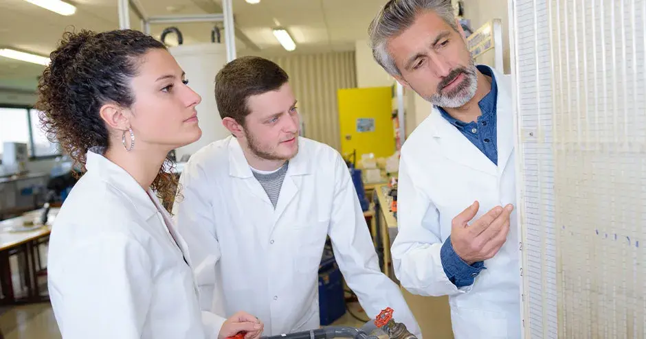 3 personas de pie en una instalación hablando sobre el trabajo