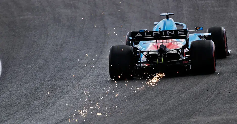 automóvil de carrera de alpine f1 en la pista alejándose con chispas que salen de la parte trasera del automóvil