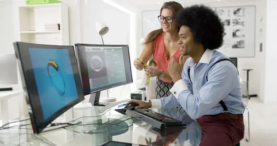 2 personas diseñando un reloj y editando el archivo en un monitor grande