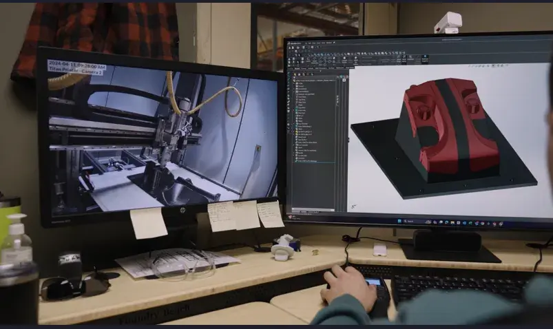 Una persona mirando un modelo CAD en 2 monitores de computadora