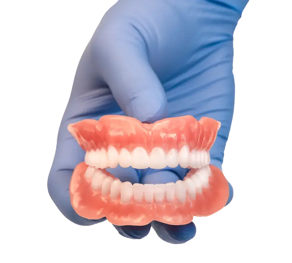 Una mano con un guante médico mostrando dentaduras impresas en 3D